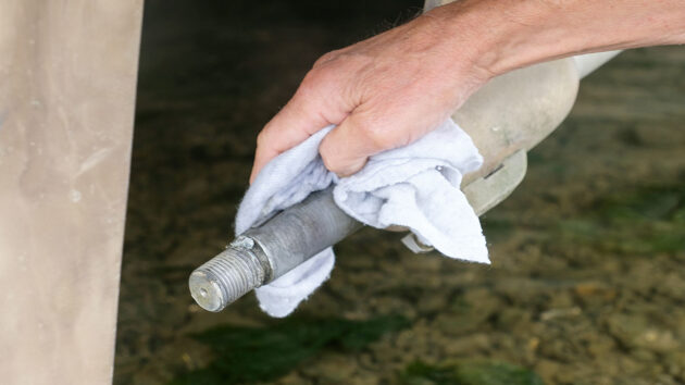 A man cleaning a propeller shaft ahead of propeller installation