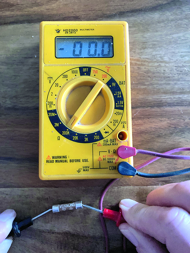A mulitmeter being used to test a fuse, as part of diagnostics to fix boat electrics