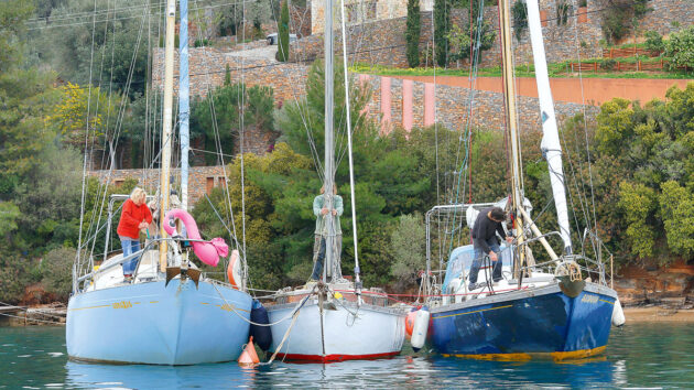 Three people preparing to unstep the mast of a boat