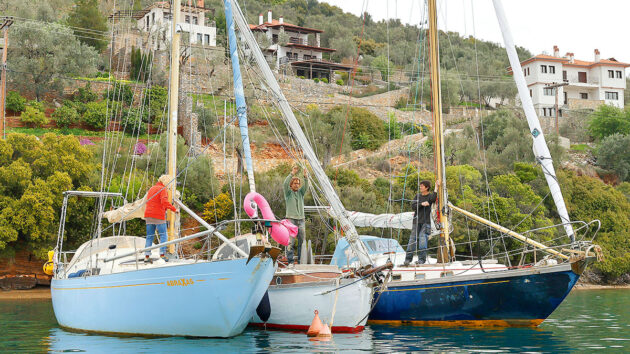 People on a boat lowering a mast