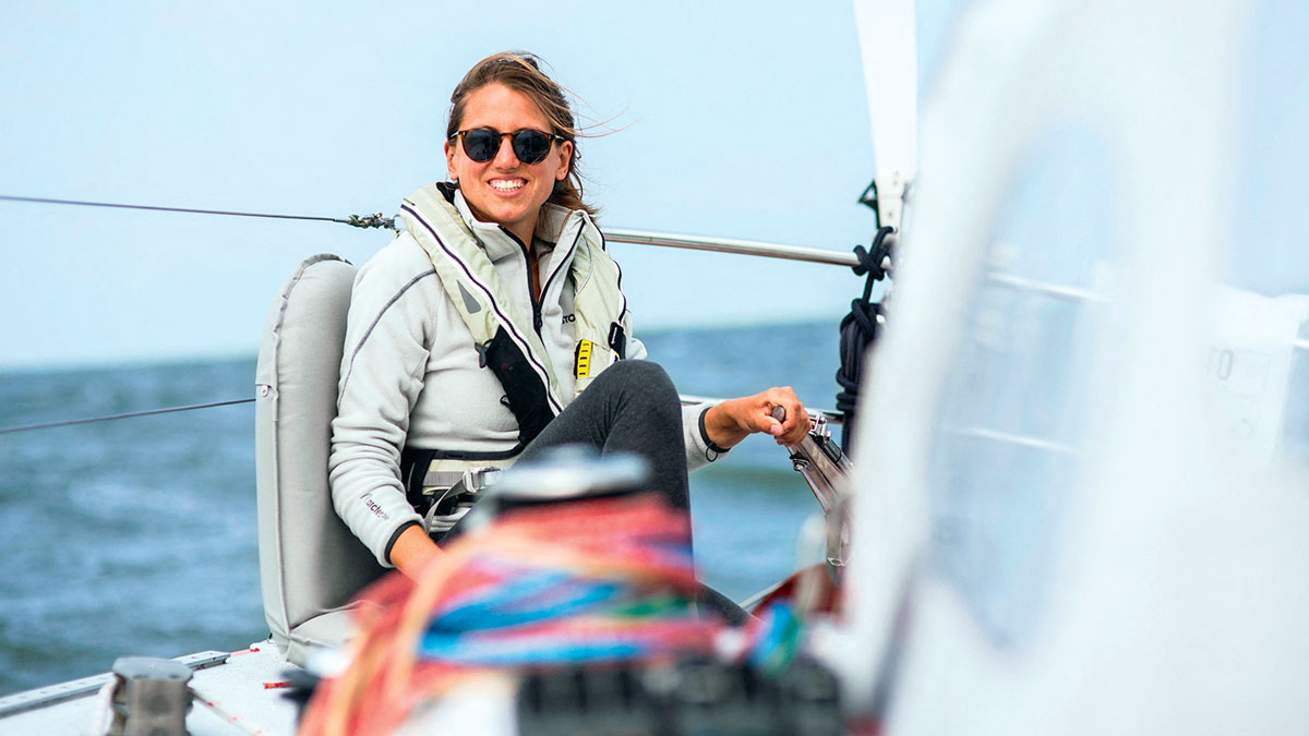 A woman at the helm of a boat sailing alone