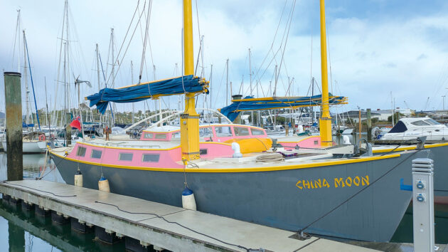 The junk-rigged catamaran boat China Moon moored in a marina