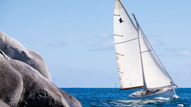 A Grand Cormoran boat sailing past rocks