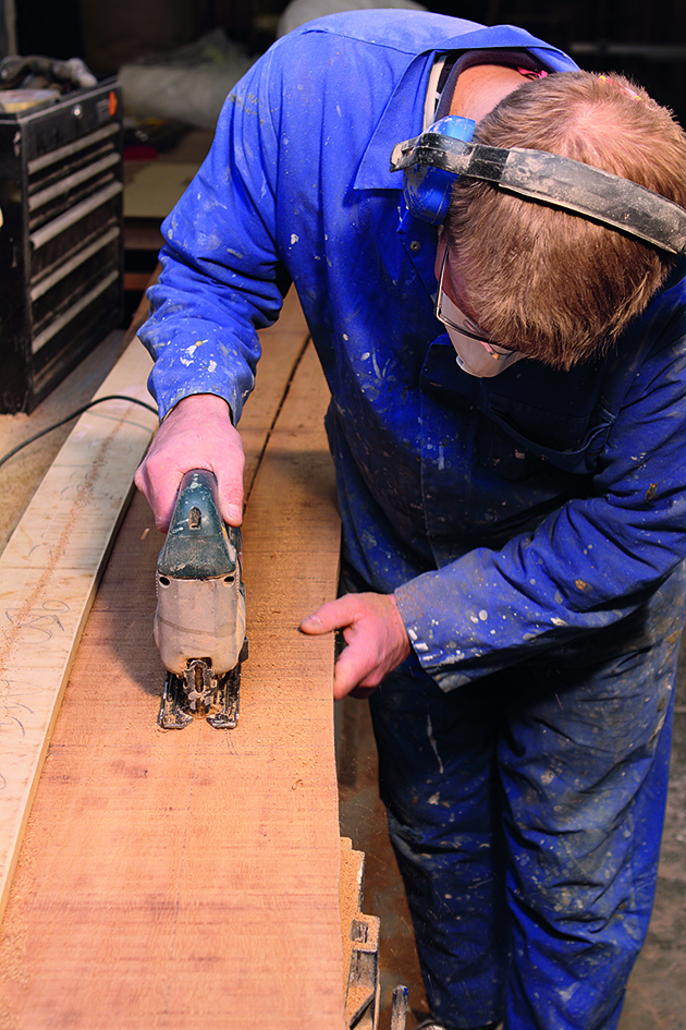 A man using a jigsaw to cut planks of wood