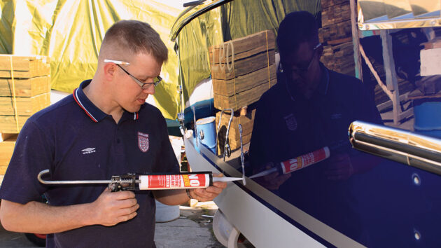 A man using silicone sealant on a boat