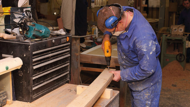A man cutting wood on a workbench to build a boat swimming platform