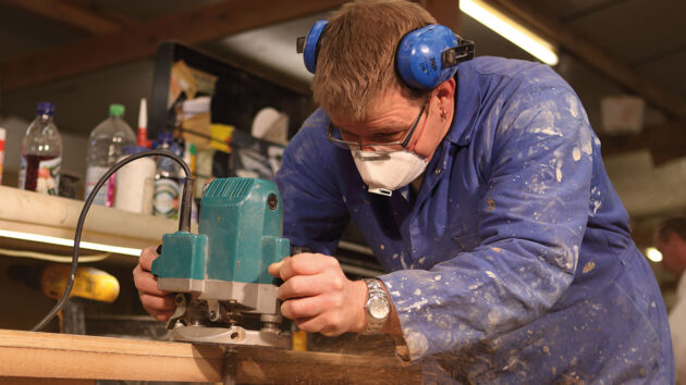 A man using a router to cut wood for a boat swimming platform