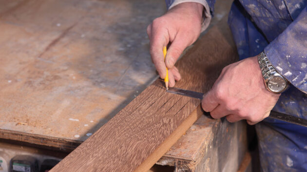 A man marking up wood for cutting