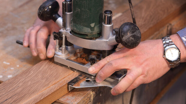 A man using a router to cut wood for a boat swimming platform