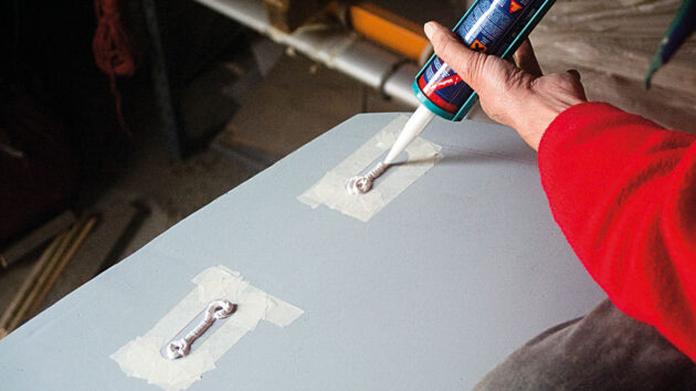 A man applying sealant to a boat to fit deck gear