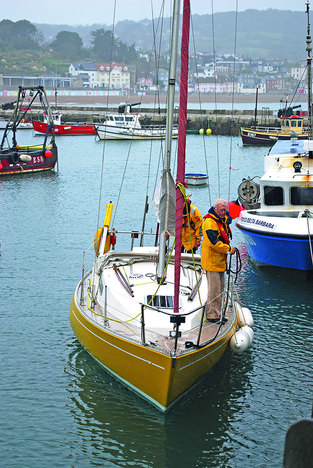 two sailors preparing lines and fenders on a yacht for drying out against a wall