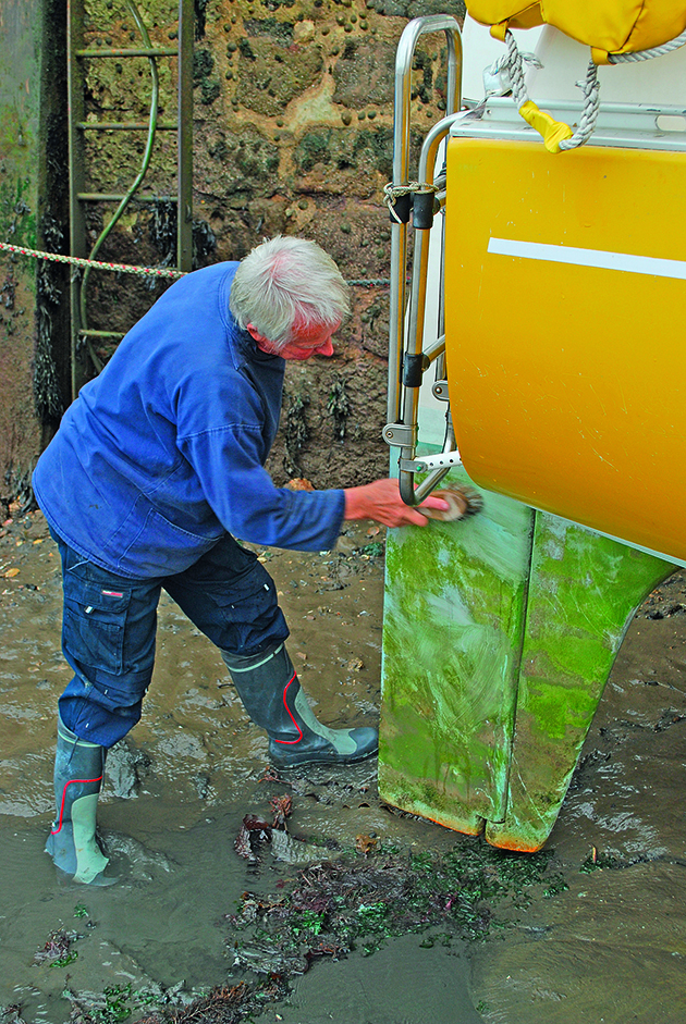 A man cleaning a rudder on a boat