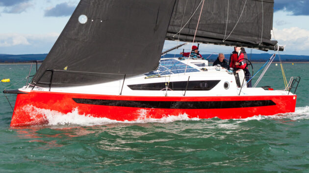 A yacht with a red hull being sailed