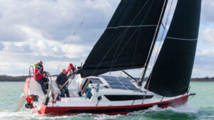 Crew sailing a w1DA yacht with a red hull and black sails