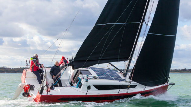 Crew sailing a w1DA yacht with a red hull and black sails
