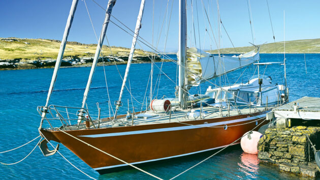 A boat with a red hull moored by a pontoon