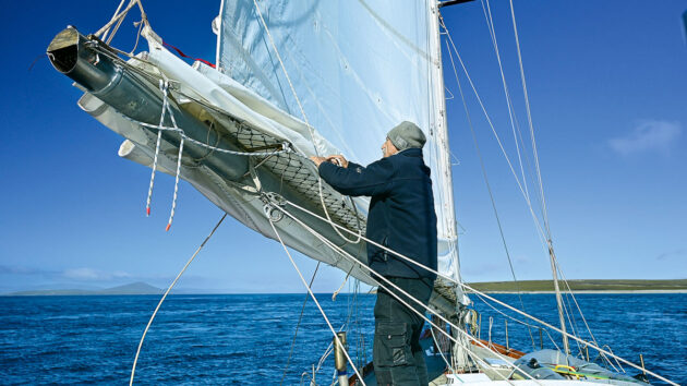 A man adjusting sails on a yacht in the Beagle Channel