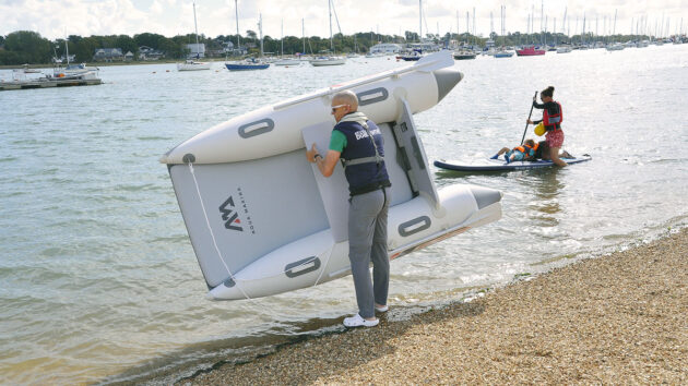 A man carrying an Aircat 280 tender to the water