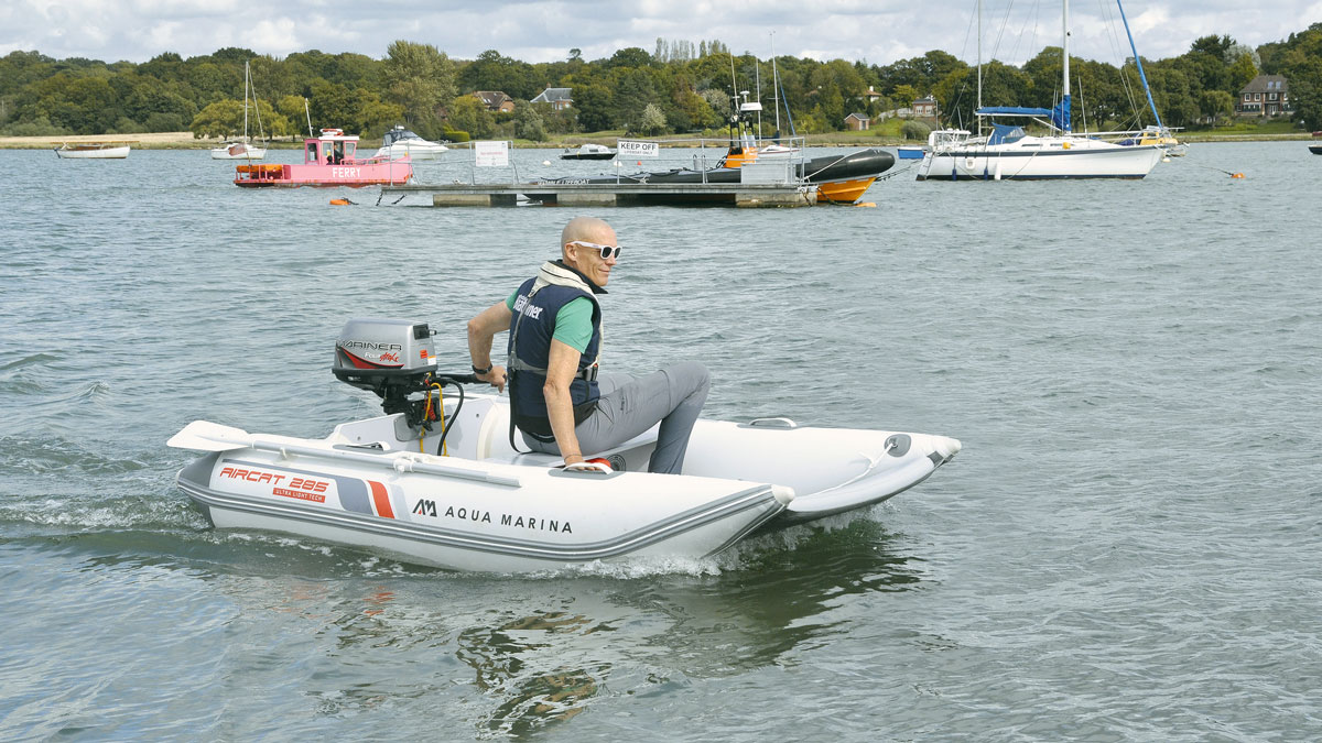 A man driving an Aircat 285 tender with an outboard engine while wearing a lifejacket