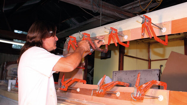 A man applying metal clamps to the side of the boat while doing building work