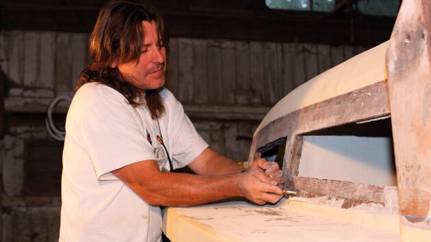 A man doing woodwork on a boat