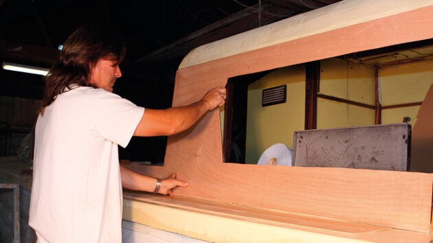 A man fitting plywood veneer to a boat