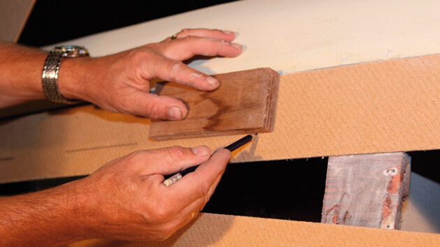 A man drawing a line on wood