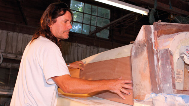 A man fitting veneer plywood to a boat