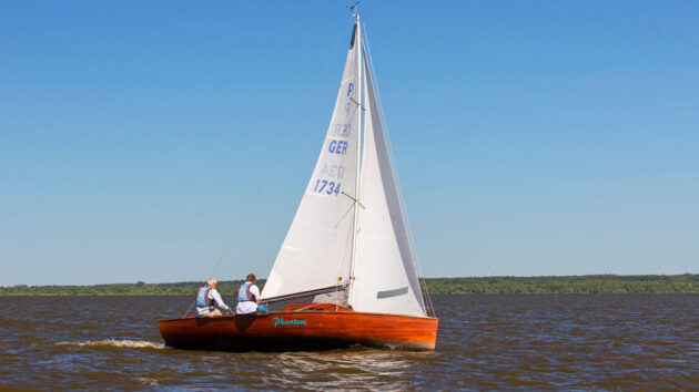 Wooden sailing dinghy with two crew. Credit: Arterra Picture Library/Alamy