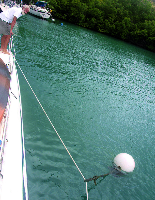 A man checking a white buoy on a boat mooring