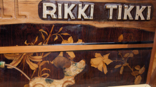 A close up of the woodwork on the yacht Collective Spirit showing a dog and the name Rikki Tikki
