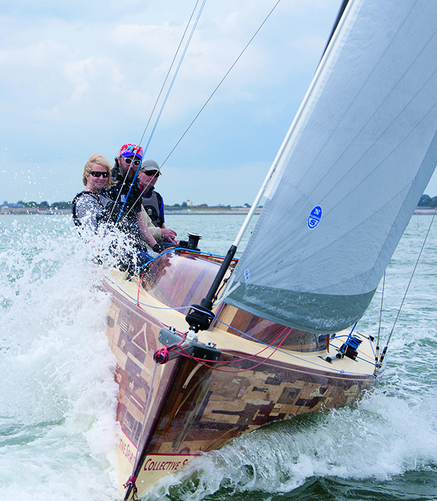 Three people sitting on the edge of a yacht while it is heeling