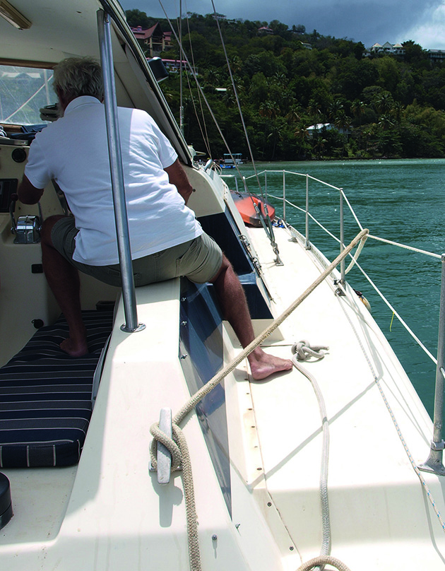 A man wearing a white t-short driving a catamaran