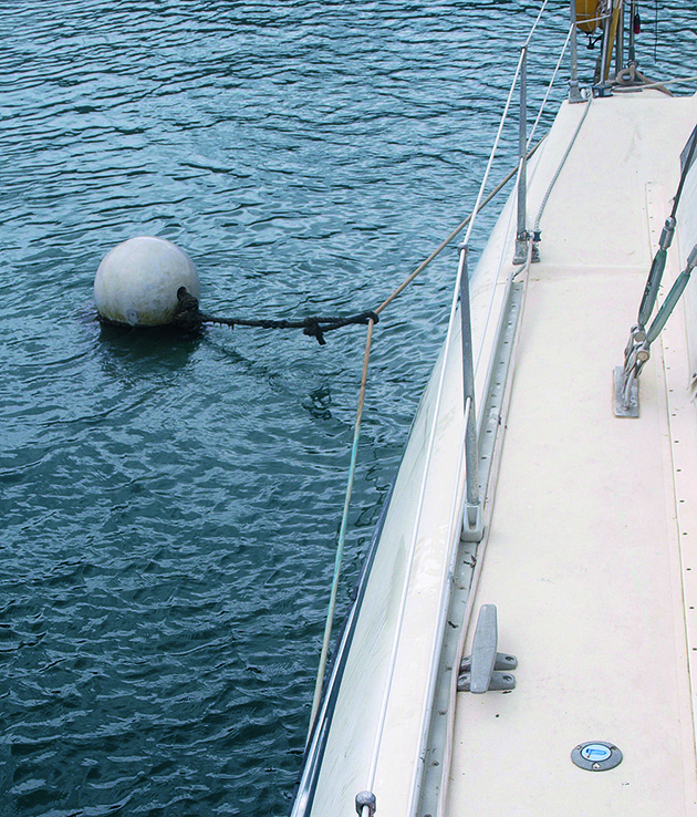 A boat alongside a white buoy for a boat mooring