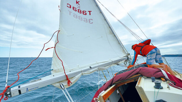 A man reefing the sails on a yacht