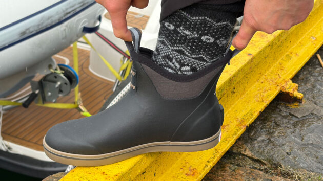 A woman pulling on a pair of XTRATUF + Finisterre Ankle Deck Boots.
