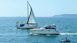 A yacht, a motorboat and a kayaker passing each other. Credit: Niki Hurrell-Head/Alamy