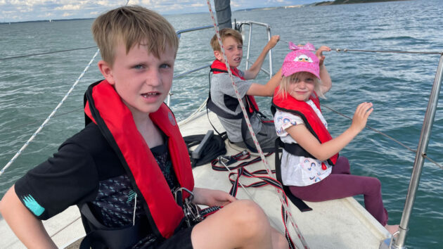 Three children on a yacht, wearing life jackets. Credit: Ali Wood