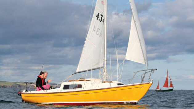 Yelllow-hulled Corribee yacht sailing with two crew onboard. Credit: Genevieve Leaper/Alamy