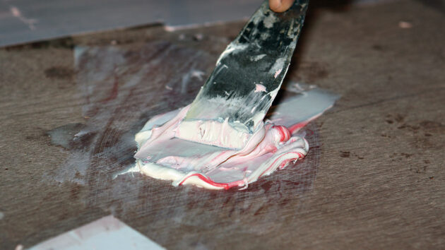 Epoxy filler being used to fill in holes on a boat
