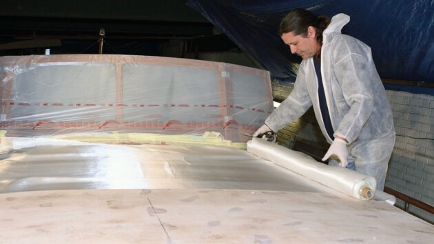 A man preparing a boat coachroof ahead of epoxy sheathing