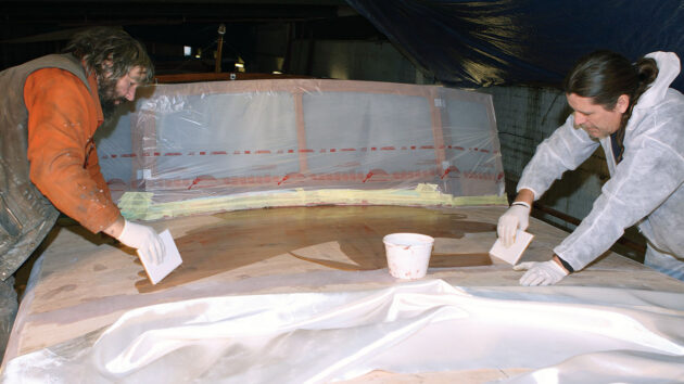 Tow men epoiy sheathing a boat coachroof
