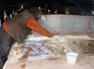 Two men epoxy sheathing the coachroof of a motor boat