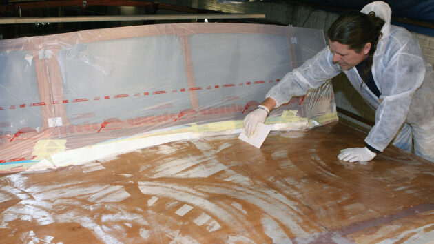 A man epoxy sheathing a coachroof of a boat