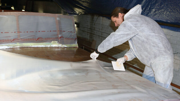 A man epoxy sheathing a boat