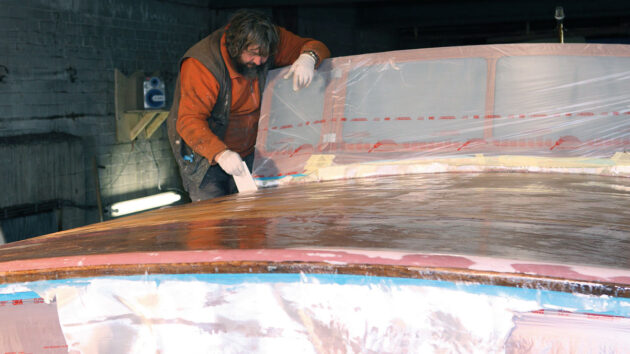A man epoxy sheathing on a boat