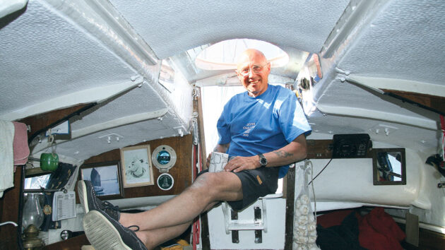 A man sitting in the companionway of his boat with the dome of the doghouse above his head