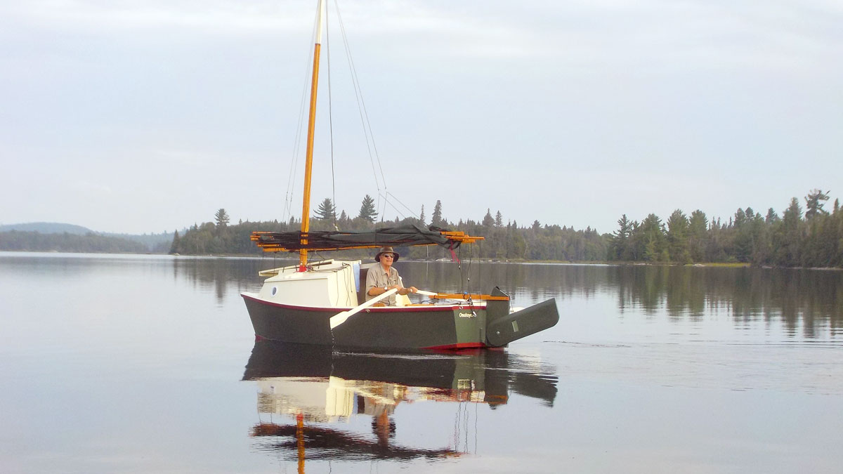 A man rowing a trailer-sailer on a lake