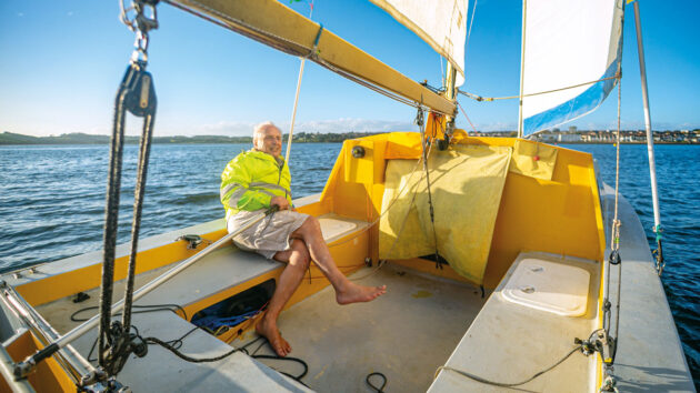 A man sitting in the cockpit of a Chat 18 catamaran