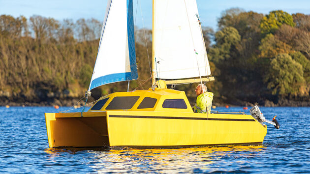 A yellow Chat 18 catamaran sailing with white sails